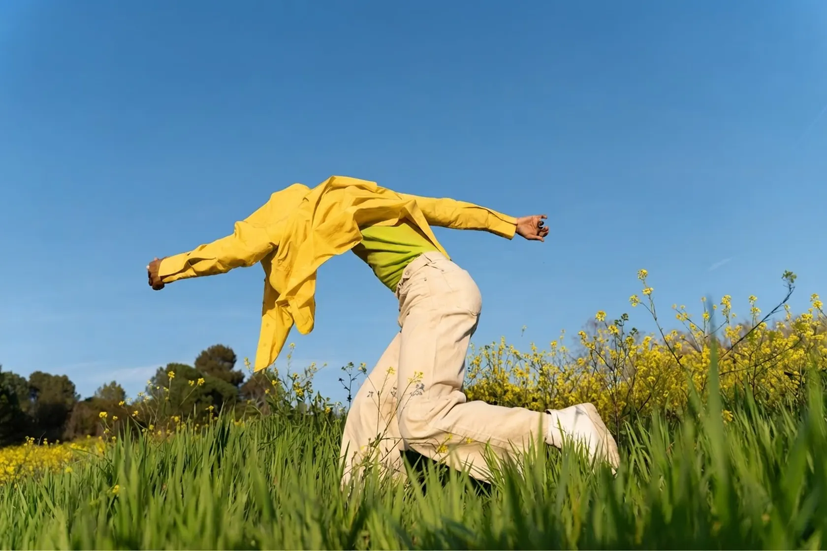 A person in a yellow jacket leaping through a wildflower field, with Fold purchase cards showing bitcoin rewards, like an $82.56 Instacart order earning 4,906 sats